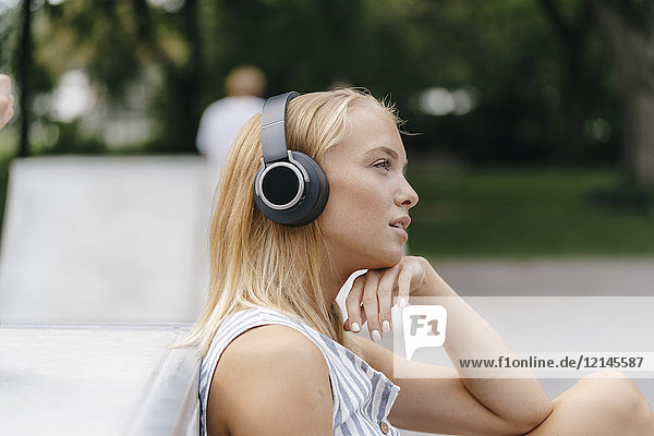 Junge Frau mit Kopfhörer beim Musikhören im Freien
