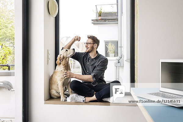 Happy man with dog sitting at the window