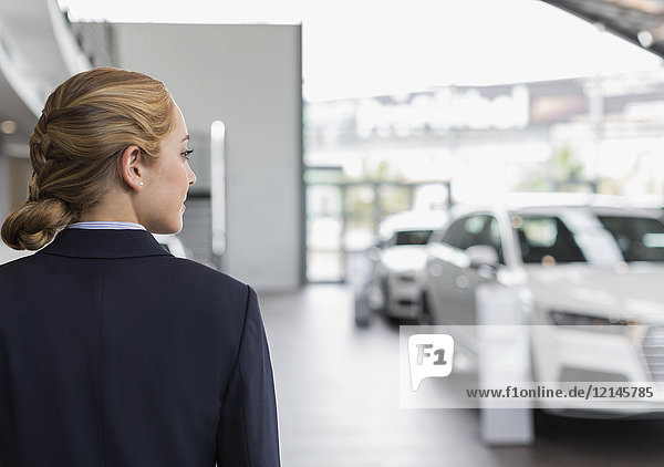 Blonde car saleswoman looking away in car dealership showroom