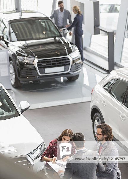 Car sales people and customers in car dealership showroom