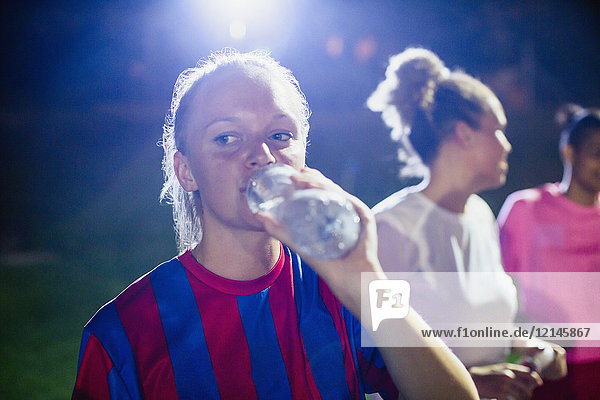 Young female soccer player drinking from water bottle