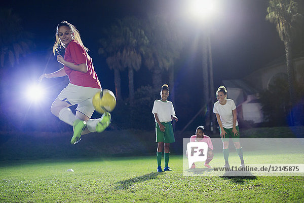Junge Fußballspielerinnen  die nachts auf dem Spielfeld trainieren und den Rückstoß ausführen