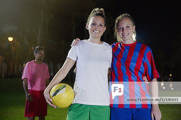 Porträt selbstbewusste  lächelnde junge Fußballerinnen mit Ball