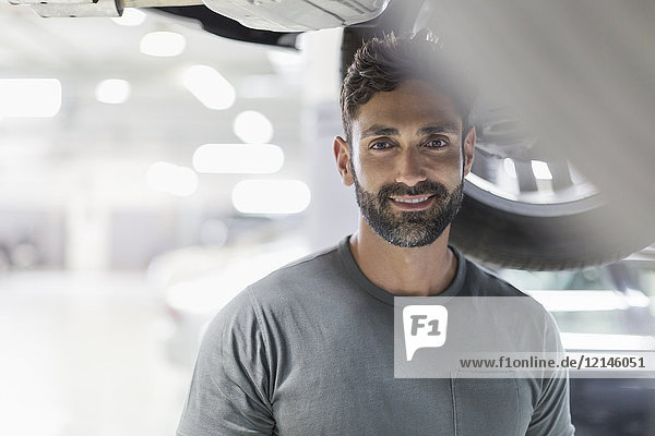 Portrait lächelnd  souveräner Mechaniker unterm Auto