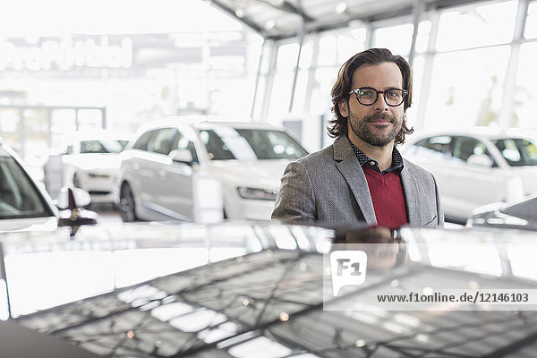Portrait smiling,  confident car salesman in car dealership showroom