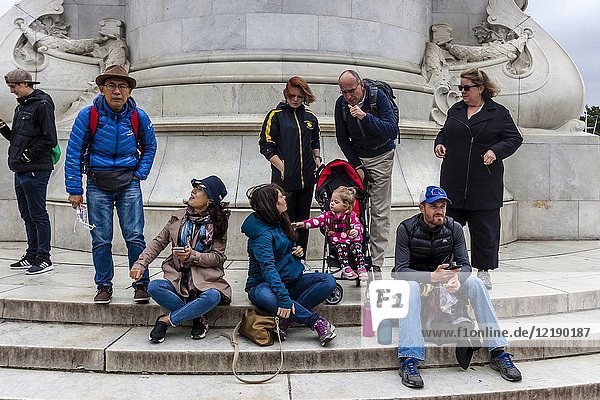 Tourists Sitting On The Steps Of The Victoria Memorial Outside Buckingham Palace  London  UK.