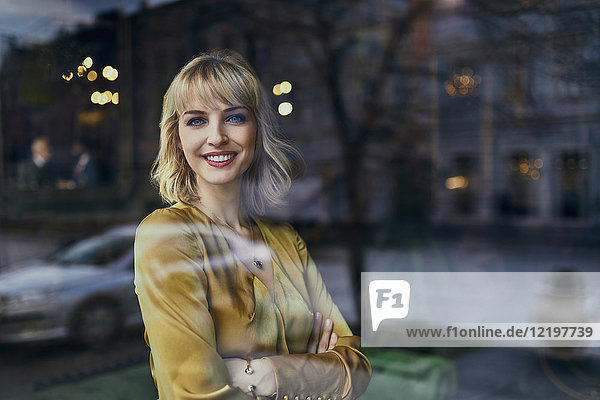 Portrait of smiling elegant woman behind windowpane