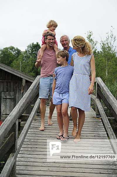 Happy family walking together on boardwalk in summer