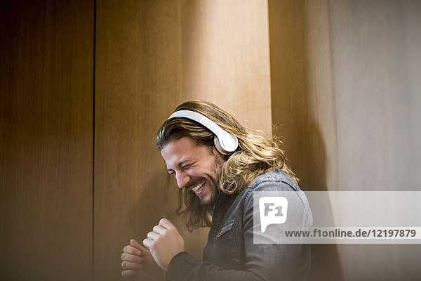 Porträt eines aufgeregten Mannes  der mit Kopfhörern Musik hört.