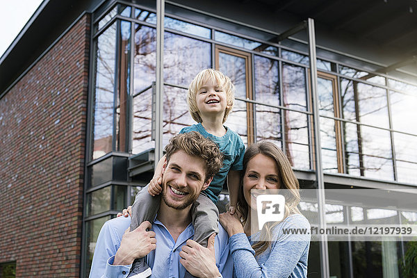 Portrait of smiling parents with son in front of their home