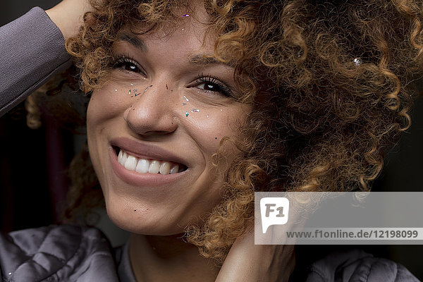 Porträt einer glücklichen Frau mit Konfetti im Gesicht
