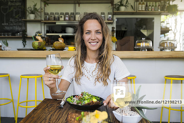 Porträt einer lächelnden Frau mit einem Glas Wein im Café