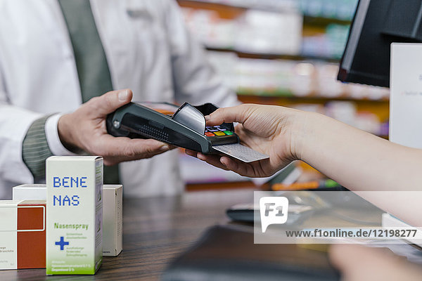 Close-up of customer paying cashless in a pharmacy