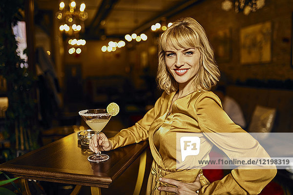 Porträt einer eleganten Frau mit Cocktail in einer Bar