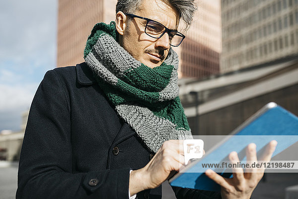 Portrait of businessman using tablet outdoors
