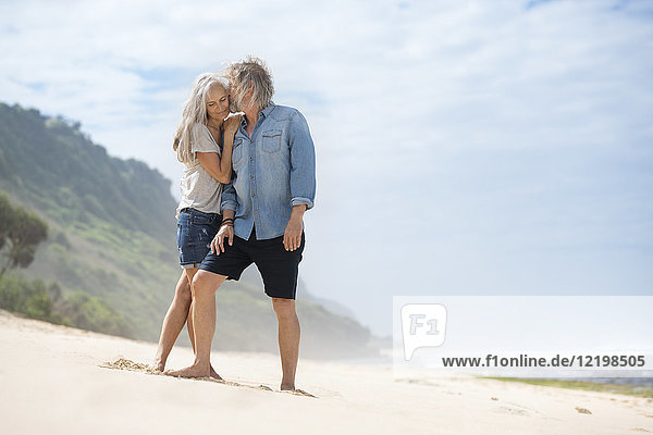 Affectionate senior couple standing on the beach