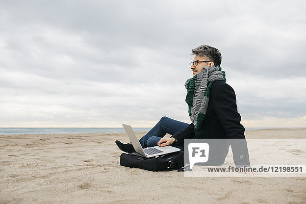 Geschäftsmann mit Laptop am Strand im Winter