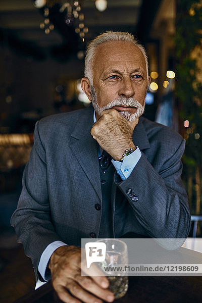 Porträt eines eleganten älteren Mannes in einer Bar mit Becher