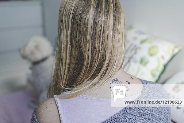 Back view of blond woman with tattoo on her neck