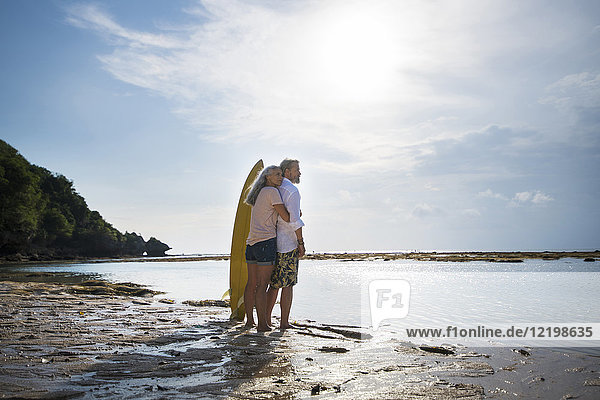 Liebevolles Seniorenpaar mit Surfbrettern am Strand