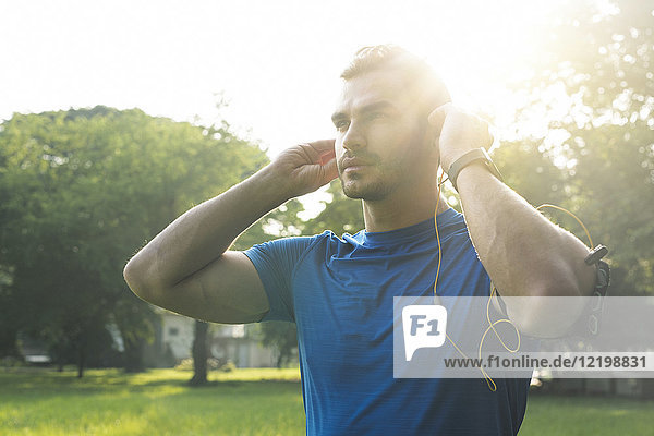 Sportlicher Mann mit Kopfhörer  Vorbereitung auf das Training im Stadtpark