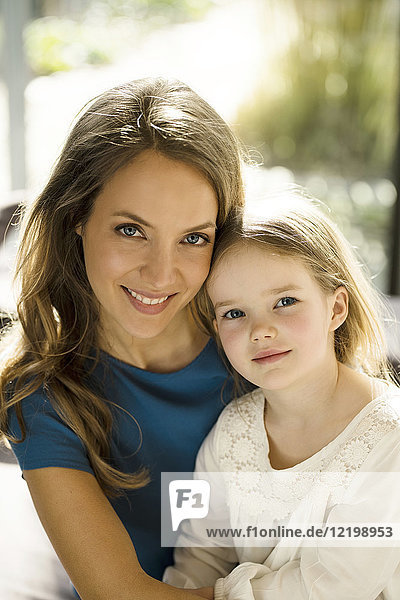 Portrait of smiling mother with daughter in front of window