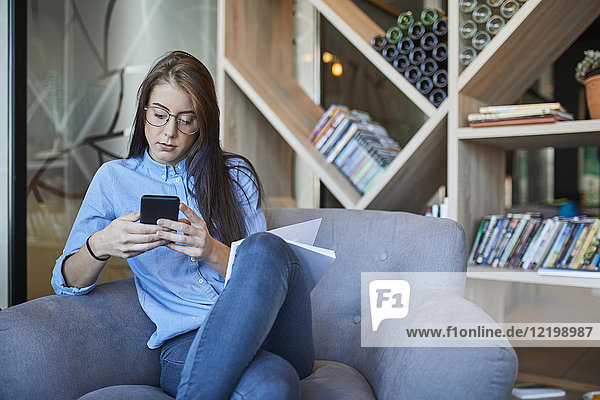 Junge Frau sitzt im Cafe mit Smartphone