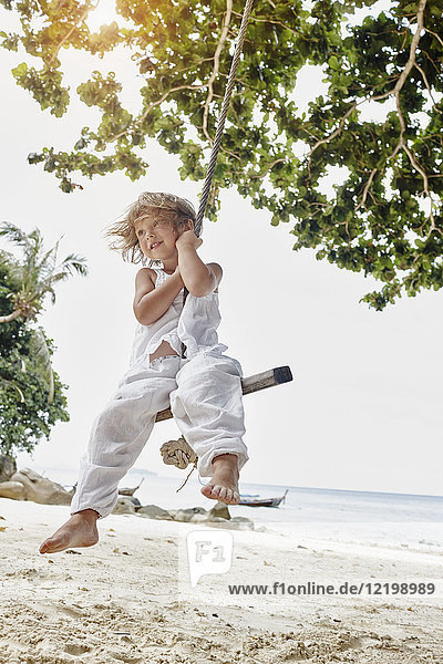 Thailand  Phi Phi Phi Inseln  Ko Phi Phi Phi  lächelndes kleines Mädchen auf einer Seilschaukel am Strand