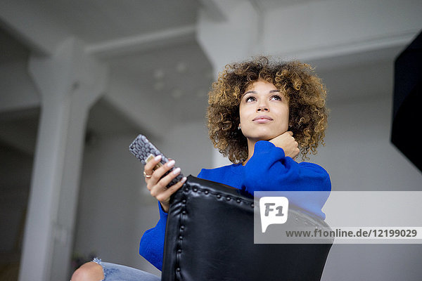 Porträt einer Frau mit Handy auf Sessel sitzend