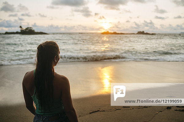 Costa Rica  Frau beobachtet den Sonnenuntergang am Strand von Corcovado