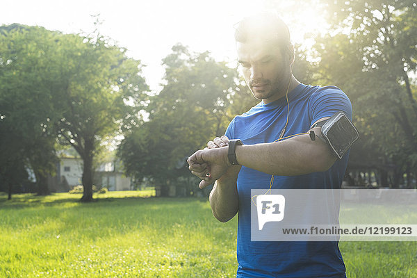 Läufer im Stadtpark überprüft seine Smartwatch