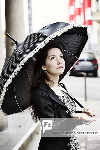 Portrait of fashionable young woman with black vintage umbrella