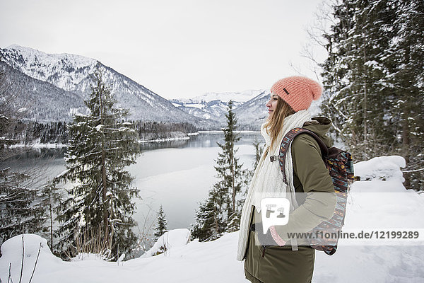 Junge Frau stehend in alpiner Winterlandschaft mit See