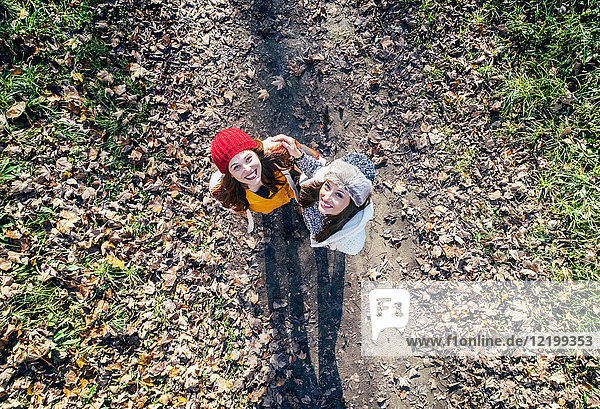 Zwei glückliche Frauen  die auf einem herbstlichen Waldweg stehen.
