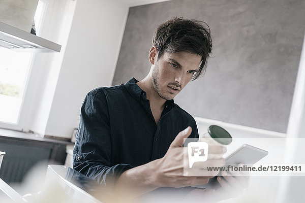 Portrait eines jungen Mannes  der eine Tablette benutzt  um Informationen über ein Produkt zu erhalten.
