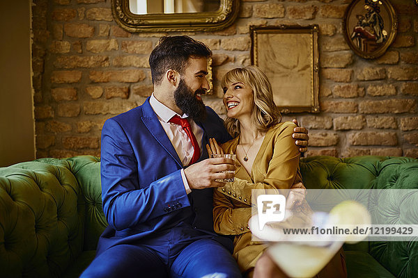 Happy elegant couple sitting on couch embracing
