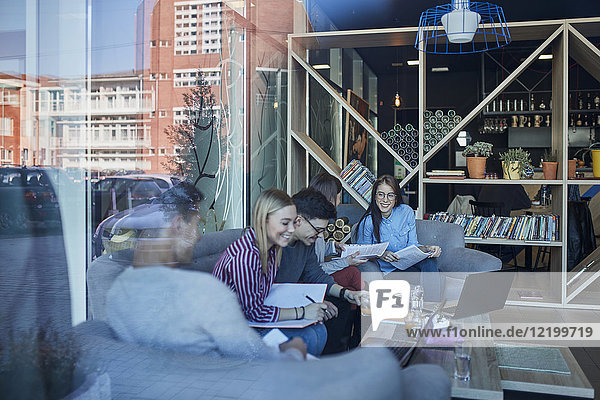 Group of friends sitting together in a cafe with reflection of glass pane