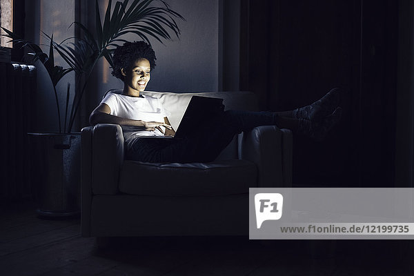 Junge Frau  die nachts online fernsieht  mit Laptop