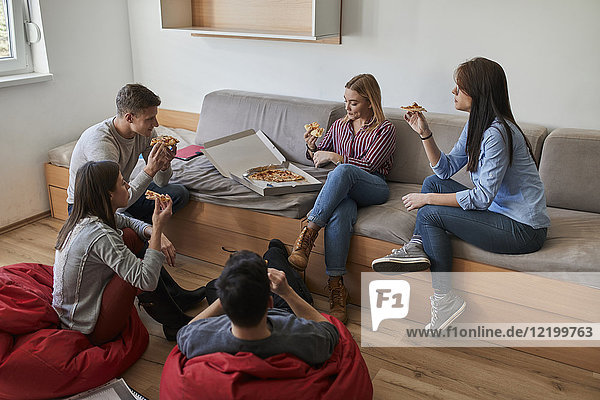 Gruppe von Schülern im Studentenwohnheim beim gemeinsamen Pizzaessen