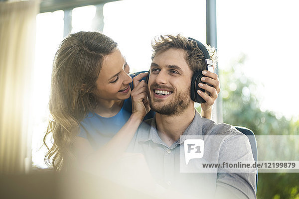 Lächelnde Frau setzt Kopfhörer auf Freund auf