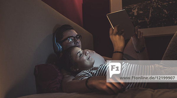 Paar liegt im Bett zu Hause und teilt sich die Tablette.