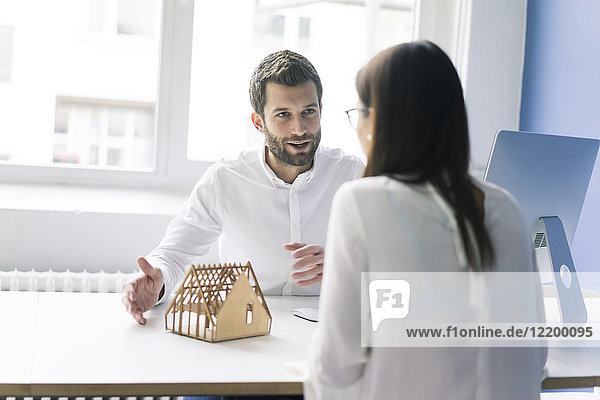 Man explaining architectural model to woman