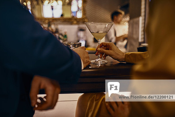 Close-up of elegant couple having a drink at the counter in a bar