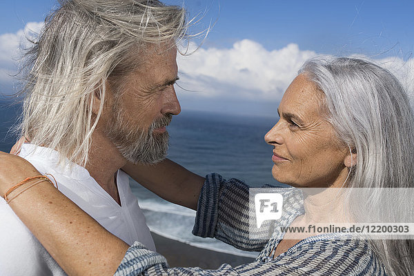Liebevolles Seniorenpaar schaut sich vor dem Meer in die Augen