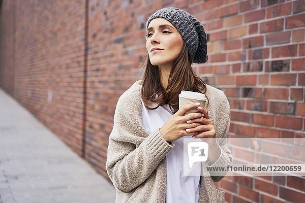 Porträt einer träumenden jungen Frau mit Kaffee zum Mitnehmen