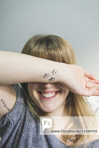 Laughing tattooed woman covering eyes with her arm