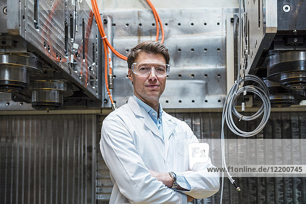 Porträt des Mannes mit Laborkittel und Schutzbrille an der Maschine