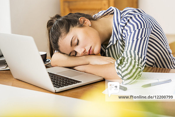 Junge Frau schläft zu Hause vor ihrem Laptop