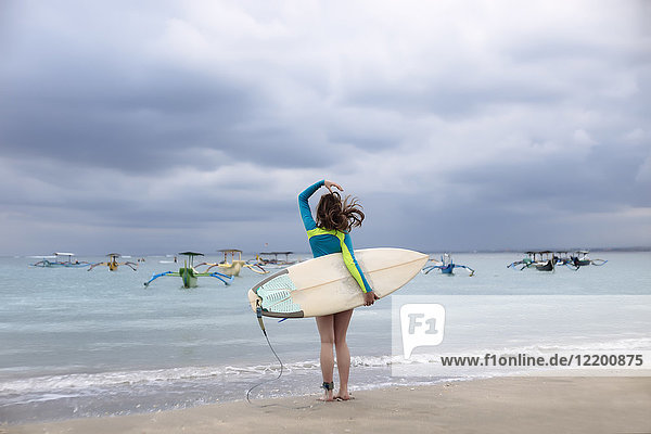 Indonesien  Bali  junge Frau mit Surfbrett
