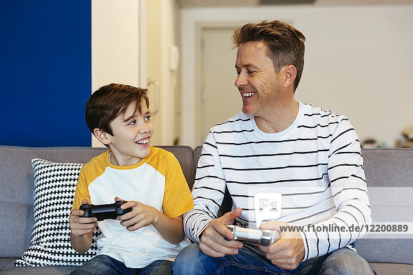 Happy father and son playing video game on couch at home